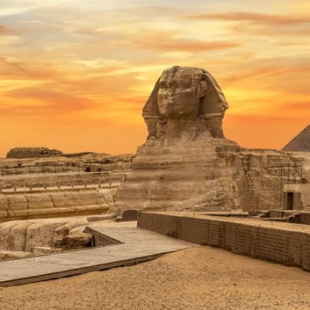 Landscape with Egyptian pyramids, Great Sphinx and silhouettes Ancient symbols and landmarks of Egypt for your travel concept to Africa in golden sunlight. The Sphinx in Giza pyramid complex at sunset